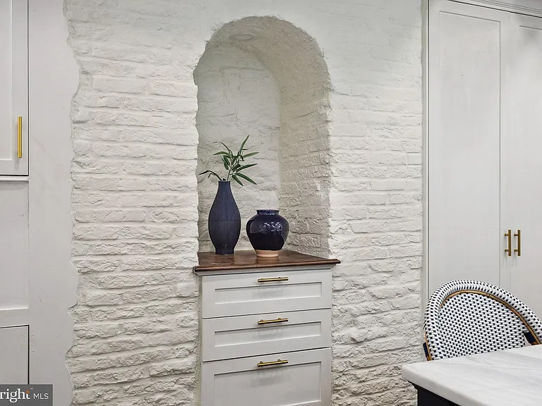 An arched niche in white-painted brick with a walnut ledge and brass pulls