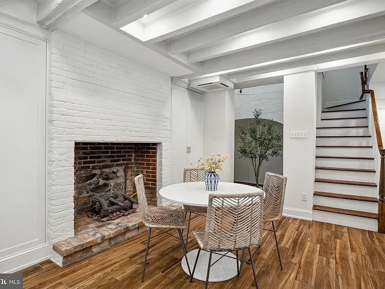 White-painted brick fireplace under painted beams