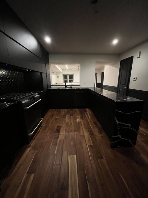 Black kitchen with waterfall island and acacia floors