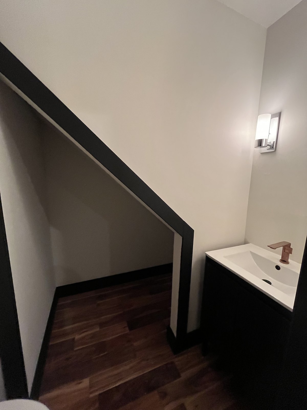 Basin tucked under the stair, copper tap